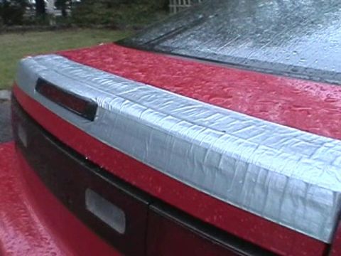 1992 Nissan 240SX - The rear of a red car shows a trunk lid that has been covered with silver tape.