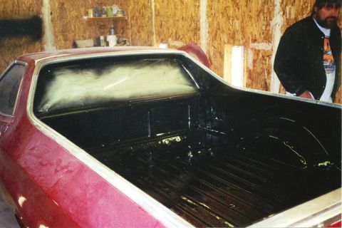 1972 Ford Ranchero - The bed of a red pickup truck is being prepared, with a man standing in the background.