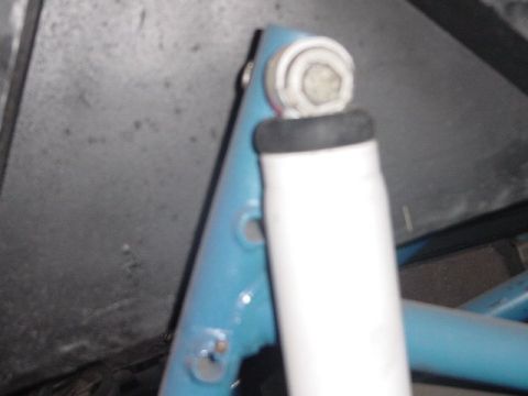 1971 Ford Bronco - Close-up of a vehicle's suspension component, showing a blue bracket and white shock absorber.