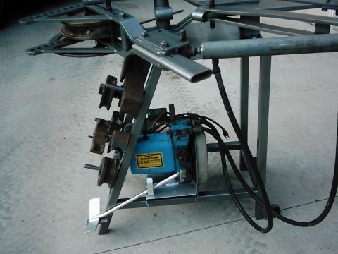 1978 Ford Bronco - Close-up of metal fabrication equipment a blue motor and various pulleys and rollers.