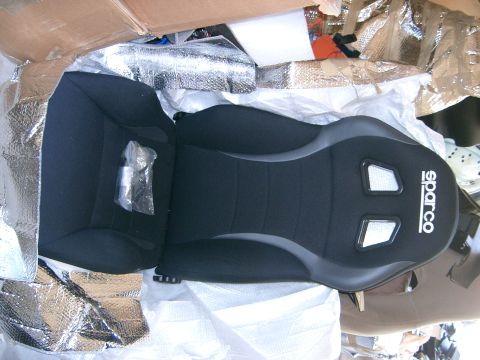 1996 Ford Probe - A black Sparco racing seat is shown, partially wrapped in reflective insulation and other packing materials.