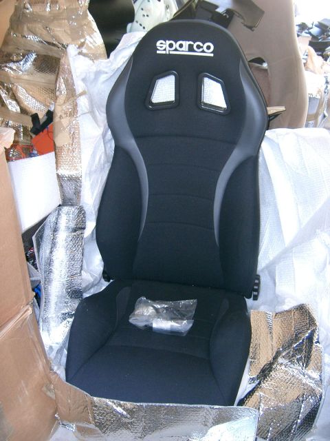 1996 Ford Probe - A black Sparco racing seat is partially wrapped in reflective insulation and cardboard packaging.