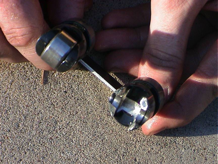Hands holding two metal engine valve lifters