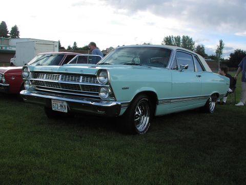 1979 Ford Bronco - A light blue 1966 Ford Fairlane coupe with a white roof is parked on grass next to other vehicles.