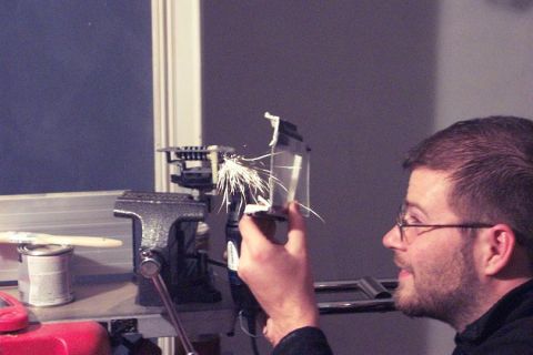 1985 Ford Crown Victoria LTD - Man uses a rotary tool to modify a small component held in a vise, creating sparks.