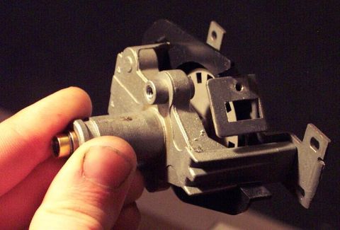 1985 Ford Crown Victoria LTD - A close-up view of a metal automotive part with a brass fitting, held by a person's fingers.