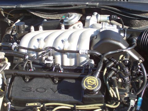 1998 Ford Taurus - The engine compartment features a Ford 3.0L V6 engine with visible spark plug wires and an oil cap.