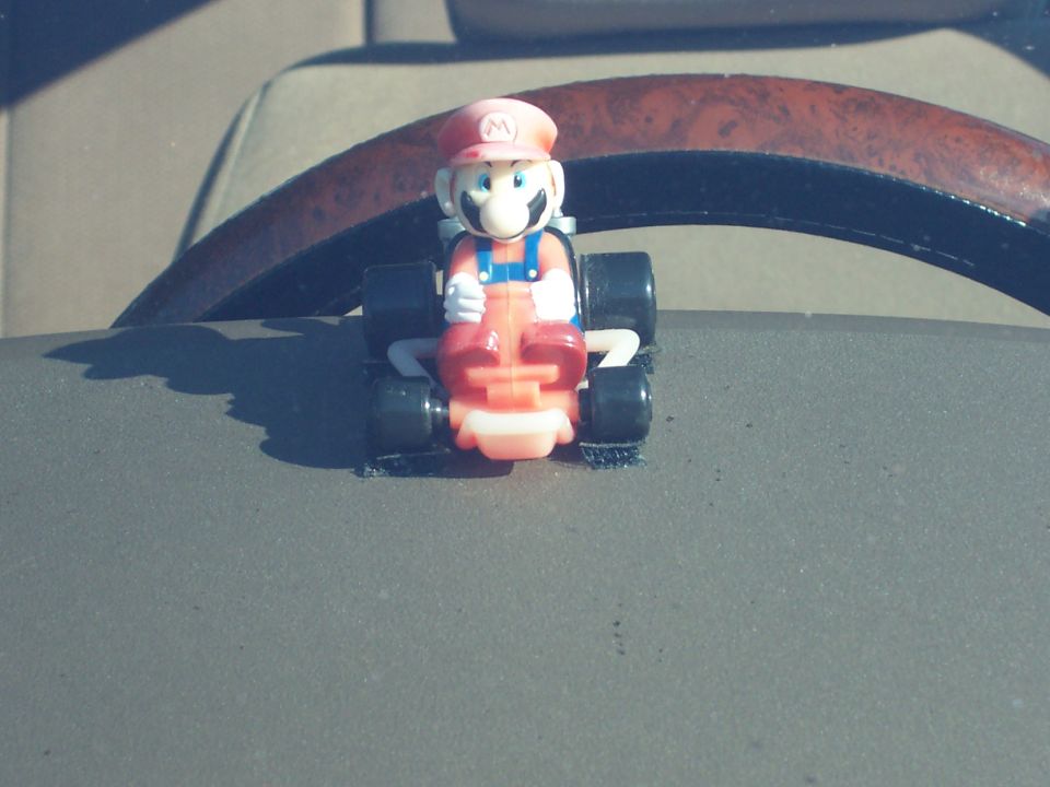 Mario toy car on dashboard in front of steering wheel