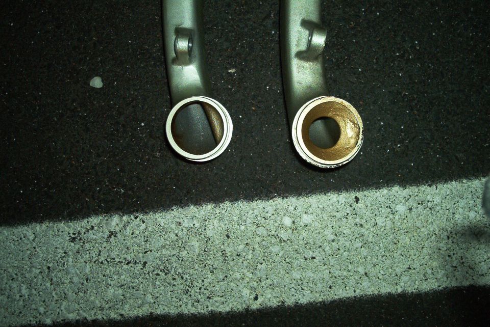 Two metal intake manifold pipes, one with a silver ring, the other with a brass bushing