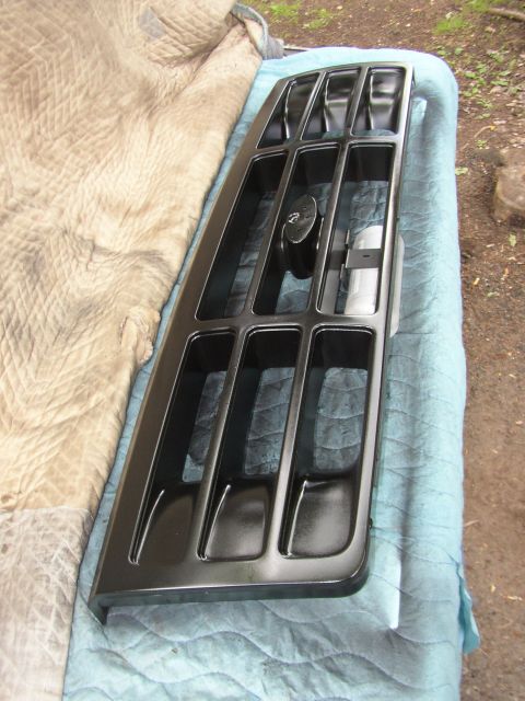 1995 Ford Bronco - A black vehicle grille is shown, resting on a blue quilted blanket outdoors.