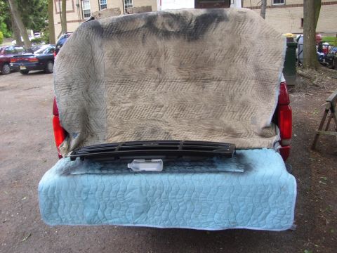 1995 Ford Bronco - A car grille is laid out on a blue quilted mat on the tailgate of a vehicle.