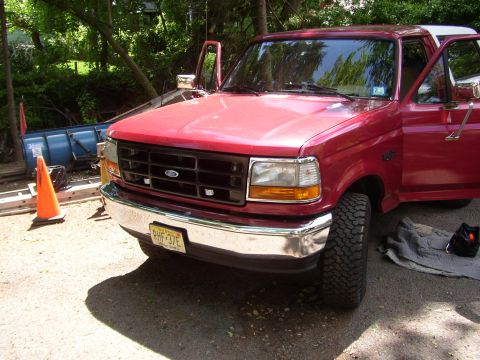 1995 Ford Bronco - Red 1995 Ford Bronco parked outside with doors open, showing its grille and front end.
