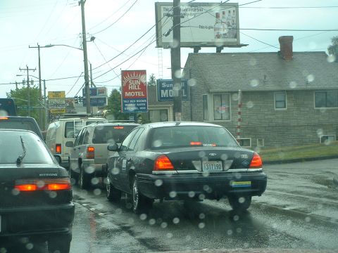 1999 Ford Crown Victoria - A 1999 Ford Crown Victoria is seen in traffic on a wet day, with several other vehicles and a motel in the background.
