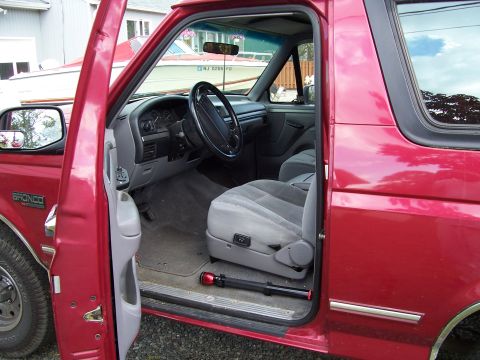 1995 Ford Bronco - Interior view of a red Ford Bronco, showing the driver's seat and dashboard.
