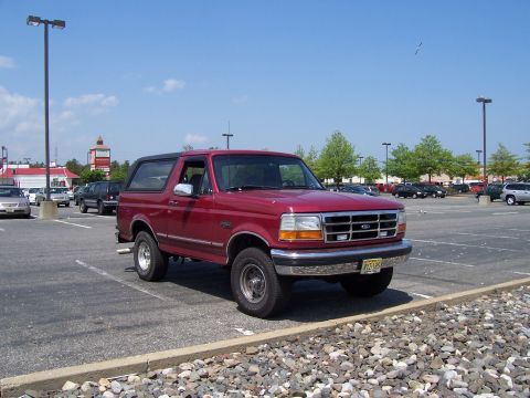 1995 Ford Bronco - Red 1995 Ford Bronco parked in a lot under a clear blue sky.