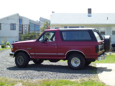 1995 Ford Bronco - Maroon 1995 Ford Bronco with black removable top and spare tire on rear.