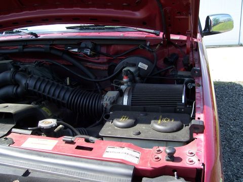 1995 Ford Bronco - The engine bay of a red 1995 Ford Bronco is visible, showing the air intake system and coolant reservoir.