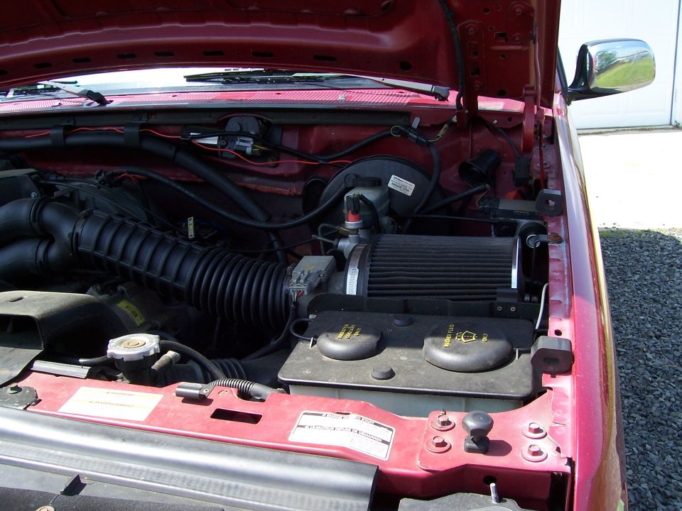Red 1995 Ford Bronco engine bay with air intake and coolant reservoir