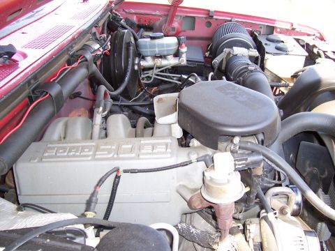 1995 Ford Bronco - The engine bay of a red Ford Bronco shows the Ford 5.0L engine and associated components.