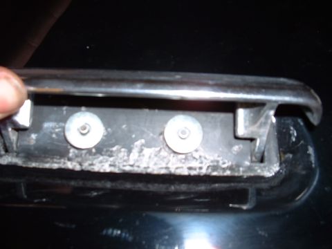 1978 Ford Mustang II - The mounting bracket for a car door handle shows signs of corrosion and wear around the screw holes.
