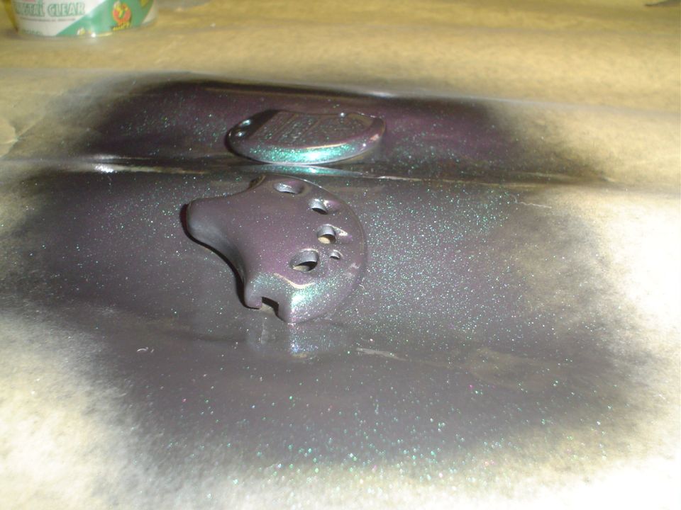 Two car key fob parts with a metallic purple and green paint job, resting on paper