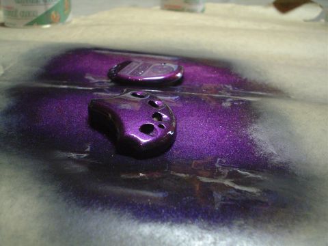 1995 Ford Taurus - Two metallic purple key fobs are shown with overspray on a surface, suggesting they are being painted.