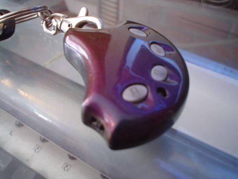 1995 Ford Taurus - A metallic purple key fob with three buttons rests on a reflective surface.