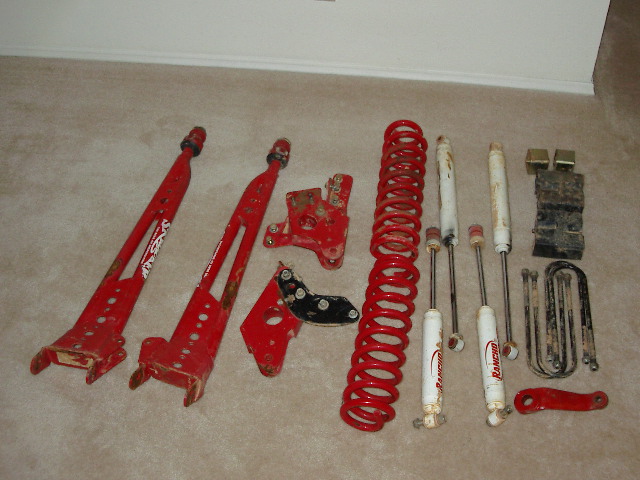 Red suspension components including control arms, coil springs, and shocks