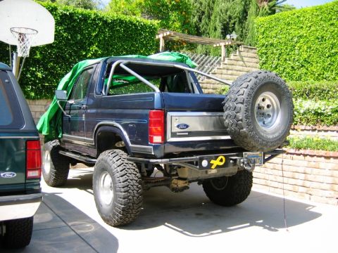1985 Ford Bronco - This lifted Ford Bronco features a custom roll cage and a spare tire on the rear bumper.