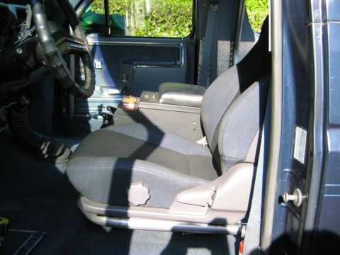 1985 Ford Bronco - The interior of a blue vehicle is visible, a patterned seat and center console.