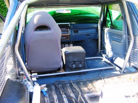 1985 Ford Bronco - The interior of a 1985 Ford Bronco features a roll cage and a racing seat, suggesting off-road modifications.