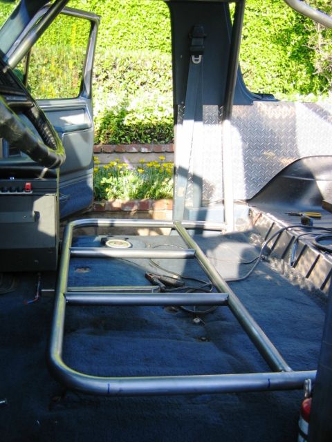 1985 Ford Bronco - Roll cage installation in progress inside a vehicle's cabin, with the driver's door open.