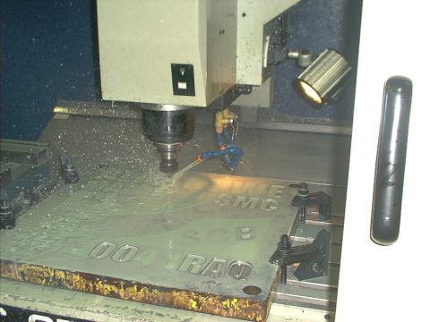 1966 Ford Bronco - A CNC machine is actively cutting letters into a metal plate, with coolant spraying onto the workpiece.