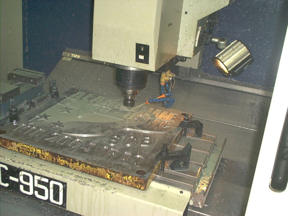 CNC machine engraving a metal plate with text and stars. Machine model C-950 visible