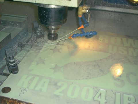 1966 Ford Bronco - A CNC machine is engraving a metal plaque with text and stars, with coolant spraying onto the workpiece.