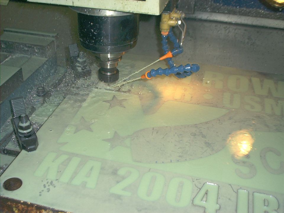 CNC machine engraving a metal plaque with text and stars