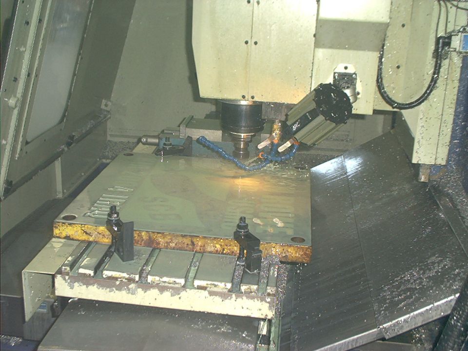 CNC milling machine cutting a metal plate with coolant spraying