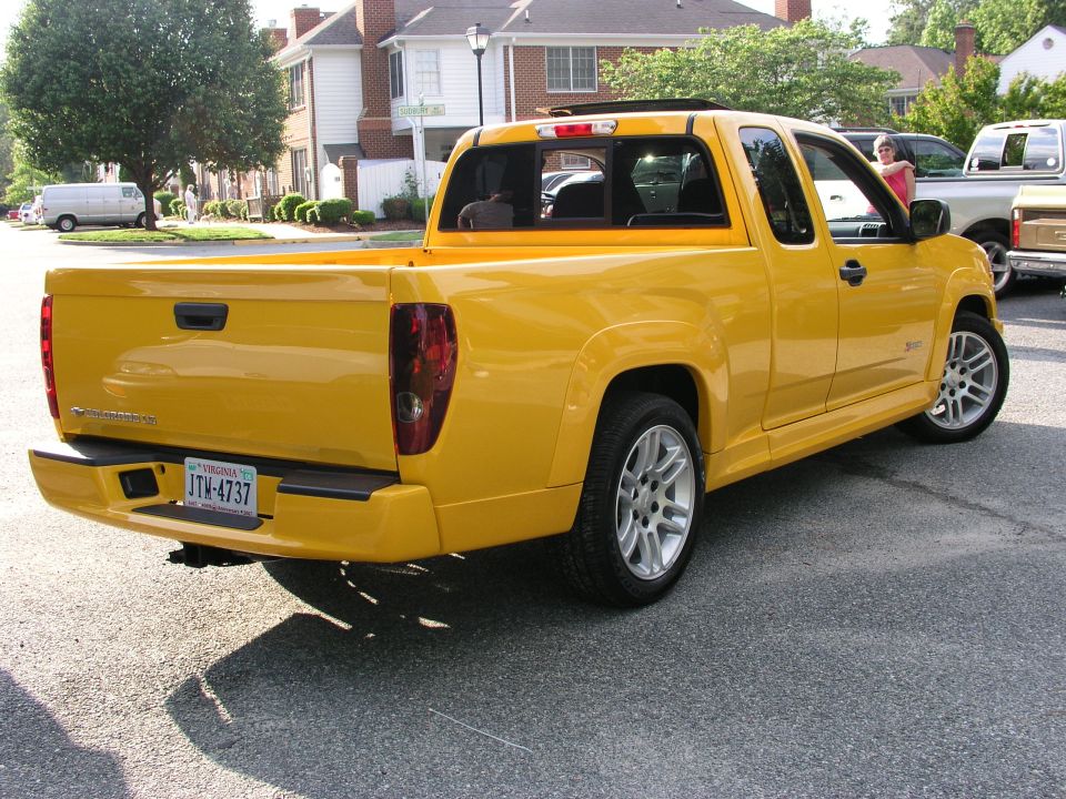 Lowered yellow Chevrolet Colorado extended-cab pickup, rear three-quarter view in a parking lot