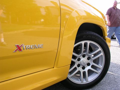 2005 Chevrolet Colorado - A yellow truck with XTREME badging and custom wheels is shown from the side.