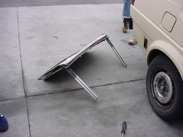 folded metal frame on pavement next to a car wheel
