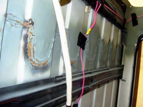 1994 Ford C-350 (Centurion Conversions) - Close-up of the interior of a vehicle, showing exposed metal panels, rust, and electrical wiring.