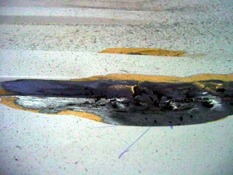 1994 Ford C-350 (Centurion Conversions) - Damaged metal panel with sealant and primer visible, likely from bodywork repair.