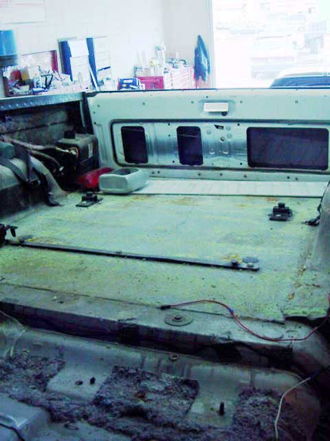 1994 Ford C-350 (Centurion Conversions) - The interior of a truck bed shows signs of disassembly, with exposed metal, wiring, and insulation visible.