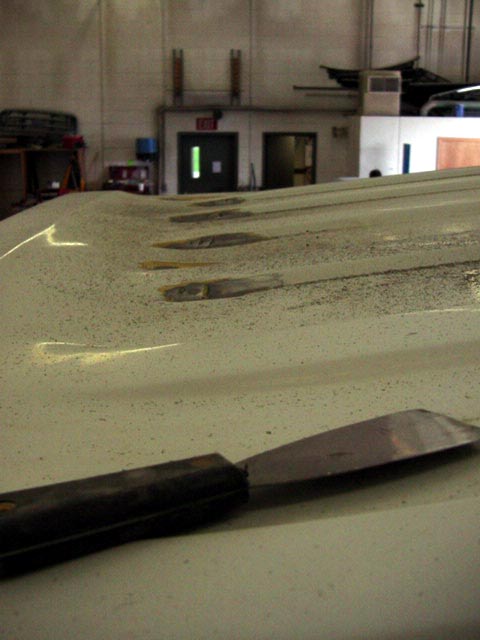 1994 Ford C-350 (Centurion Conversions) - A putty knife rests on a vehicle's roof panel, which shows evidence of welding or repair work.