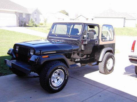 1995 Jeep Wrangler - A black 1995 Jeep Wrangler with a tan soft top is parked in a driveway.