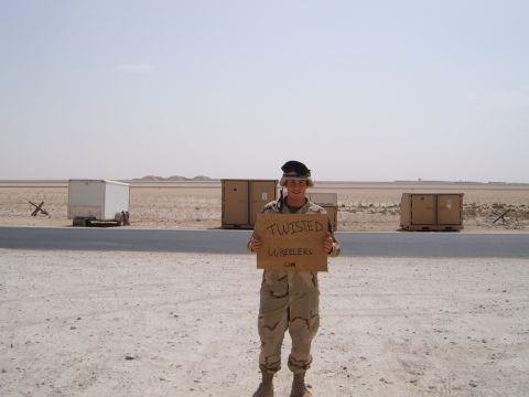 1988 Ford Bronco - Soldier in desert uniform holds a sign with a website address in a barren, outdoor location.
