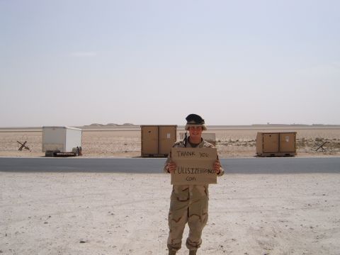 1988 Ford Bronco - A soldier holds a sign in a desert environment with shipping containers in the background.