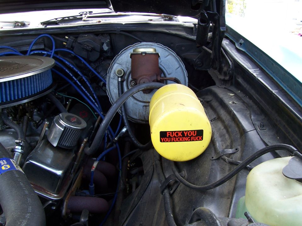 Engine bay with yellow fluid reservoir sticker reading 'FUCK YOU YOU FUCKING FUCK'