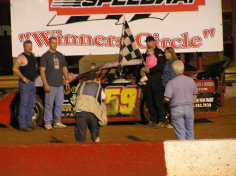 1979 Ford F-150 - A group of people celebrate with a race car and a checkered flag after a race.
