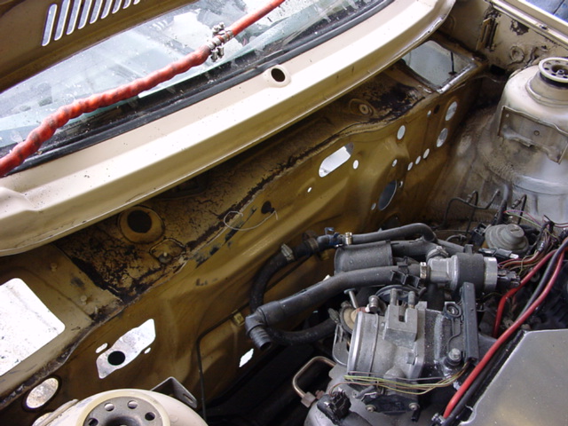 Car engine bay with hoses and wiring visible